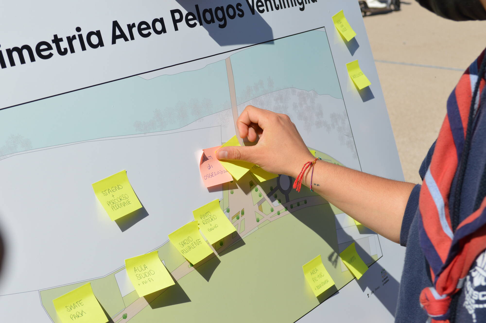 un partecipante al progetto "lo spazio pubblico" affigge un post it su una mappa della zona da valorizzare
