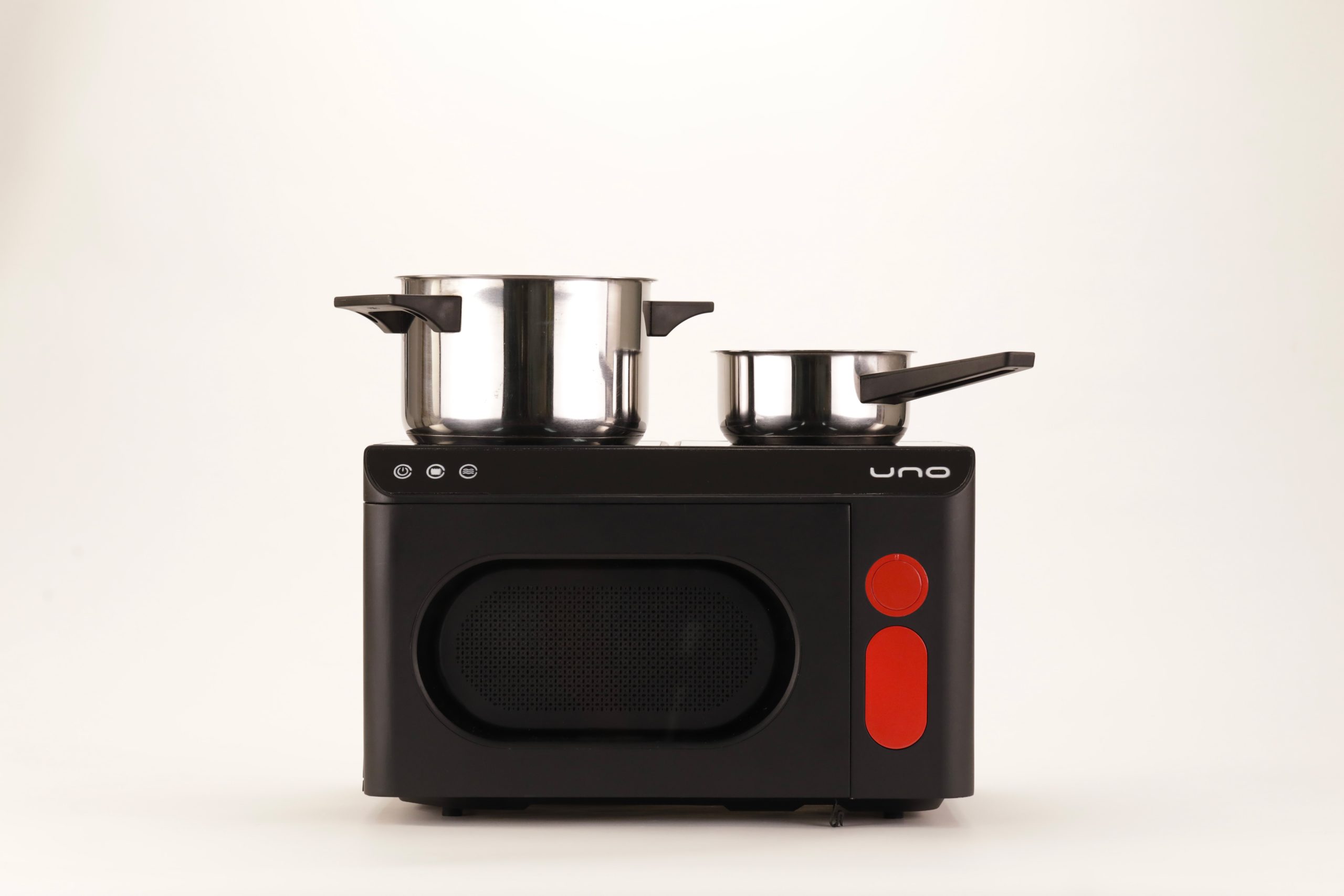 Due pentole in acciaio su mini forno nero con dettagli rossi su sfondo bianco.