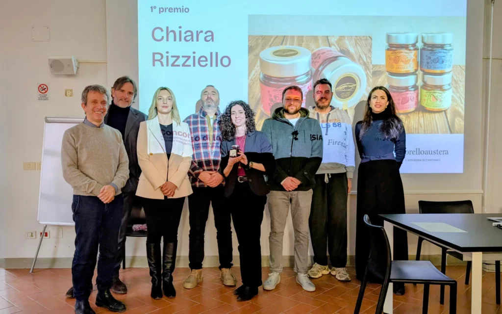 Gruppo di persone posa in piedi davanti a una presentazione con premi esposti su uno schermo dietro di loro.