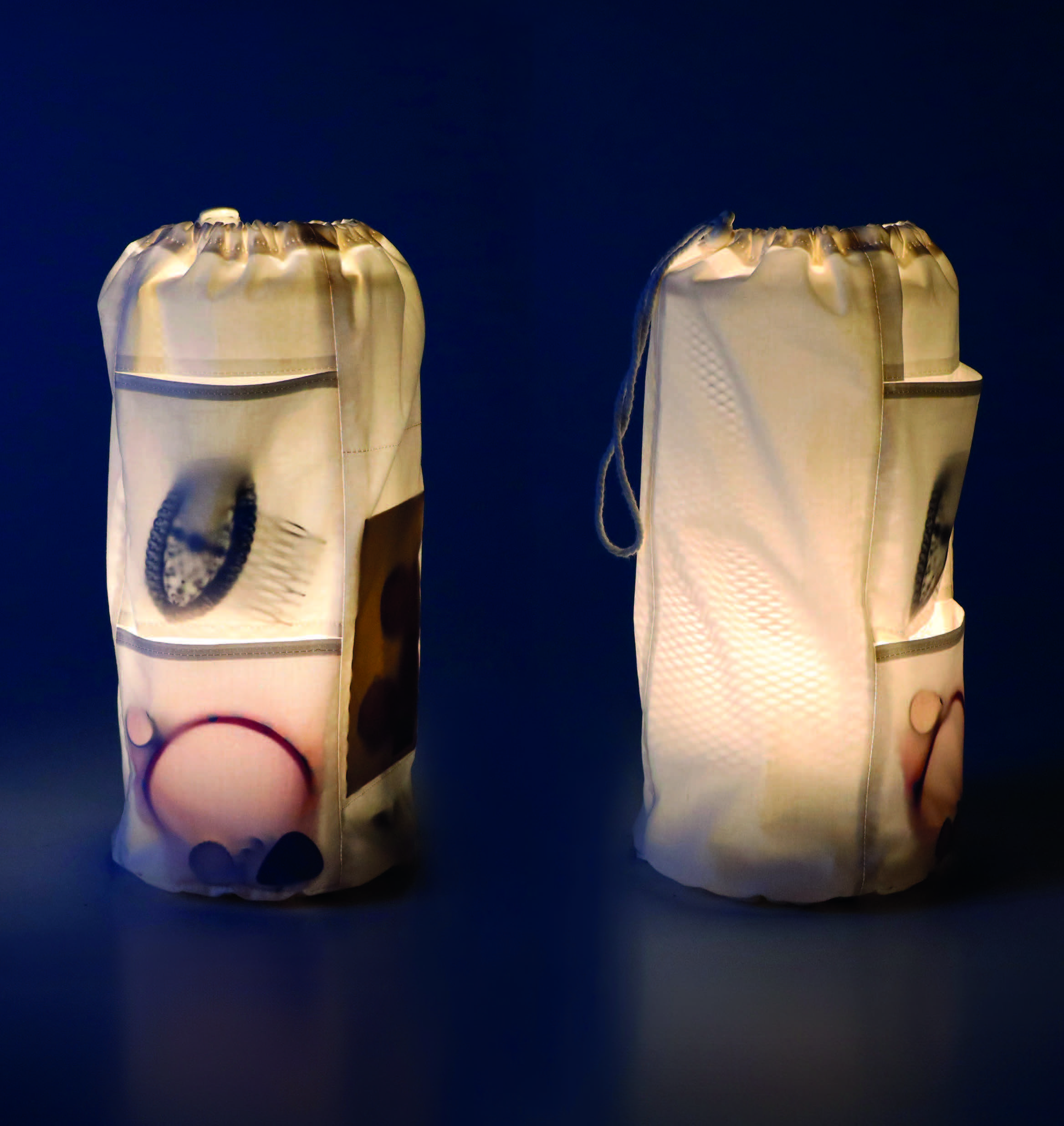 Due lanterne di stoffa bianche illuminate, con motivi circolari colorati su sfondo scuro.