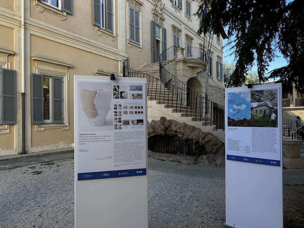 Mostra all'aperto di design e architettura davanti a un edificio storico con pannelli informativi esposti.