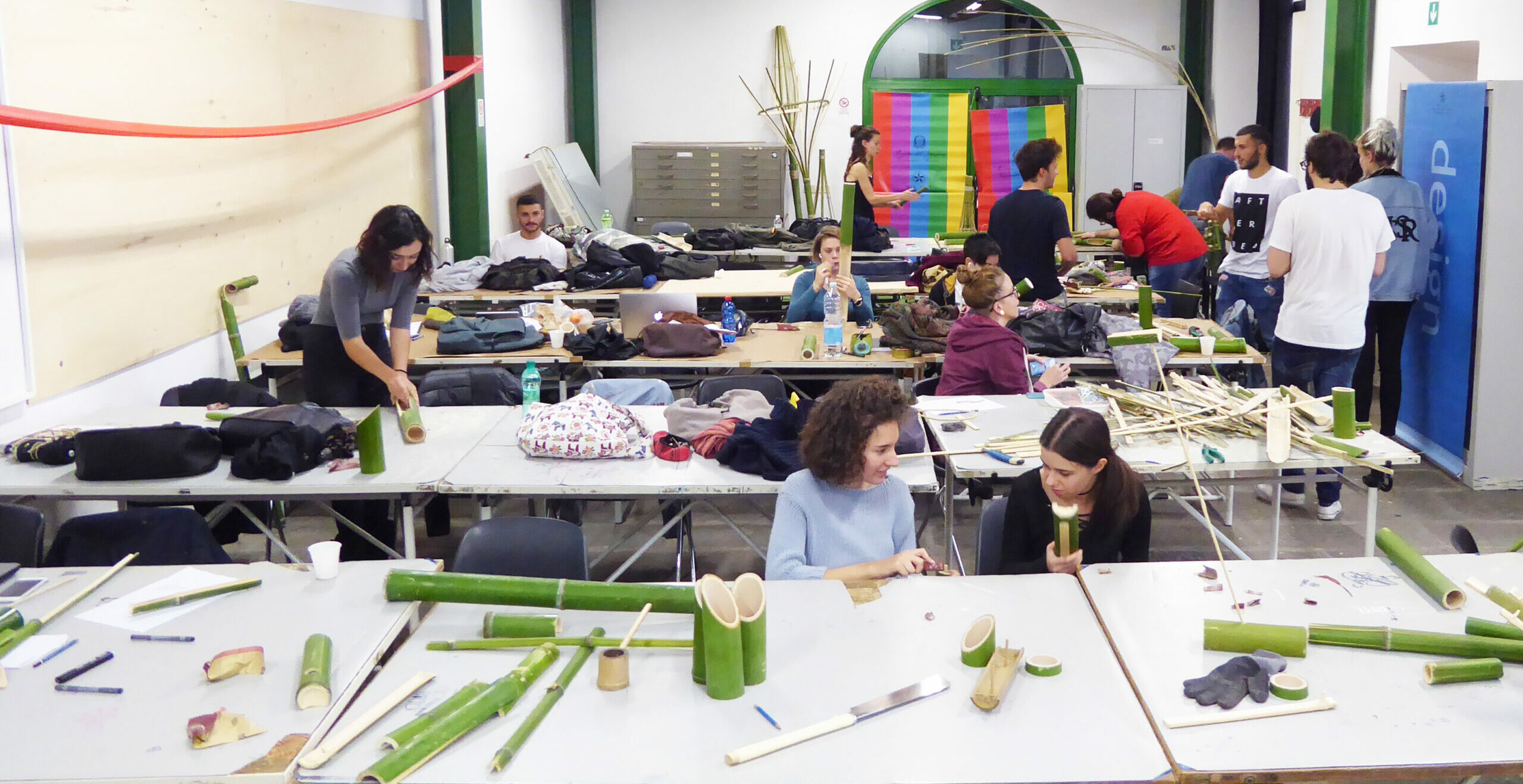 Laboratorio creativo: persone creano oggetti con bambù in un'aula con tavoli e strumenti.