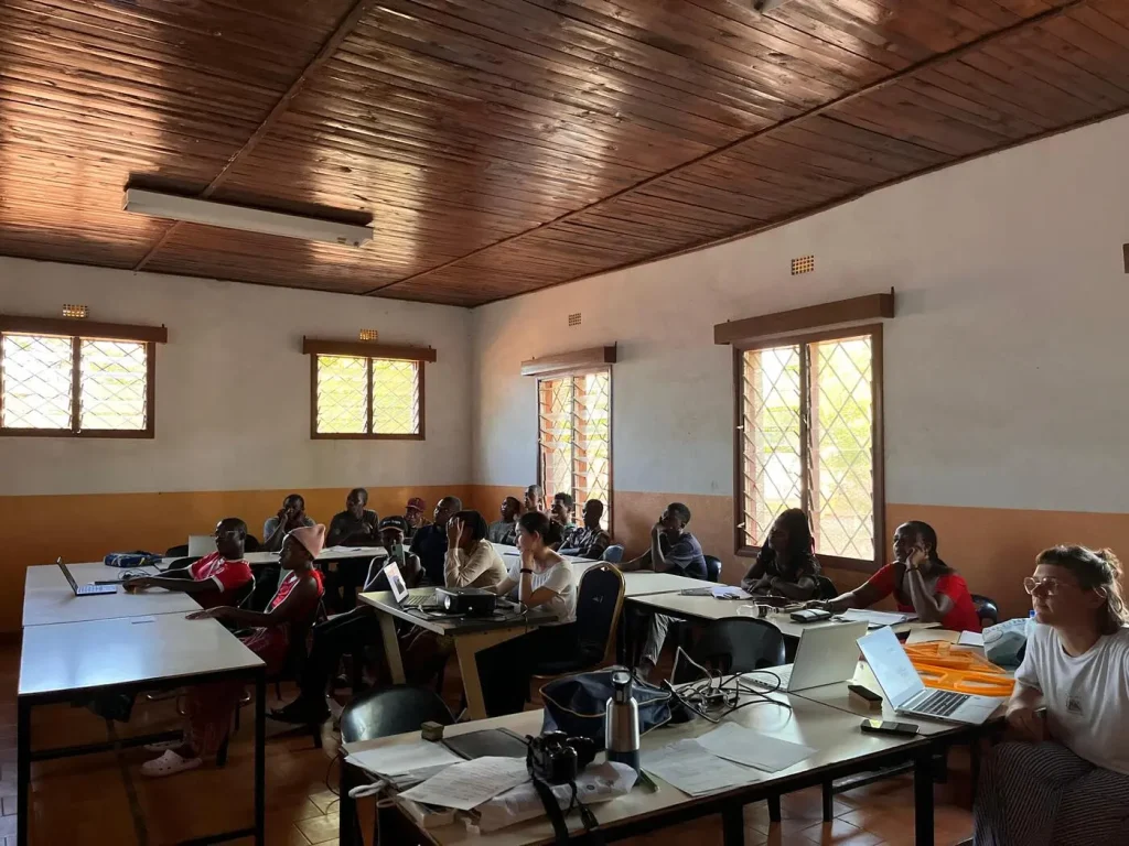 Persone in aula con laptop, seguono una lezione; un ambiente di apprendimento collettivo e partecipativo.